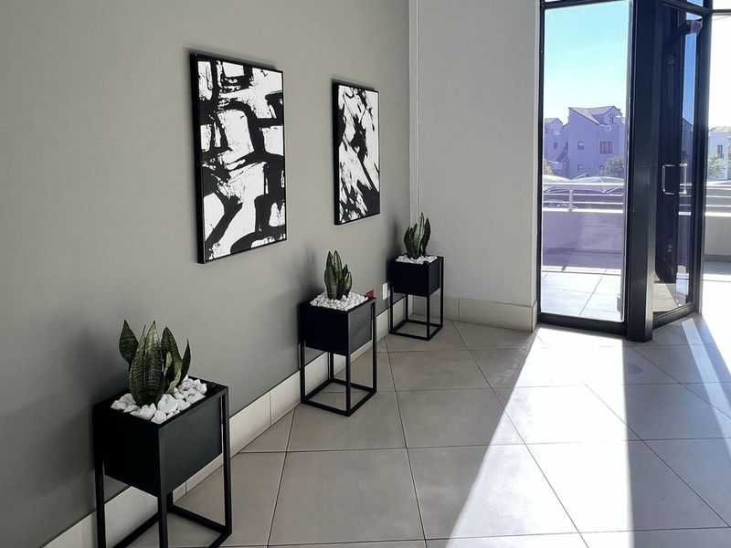 A bright and modern commercial entry area featuring neutral wall tones, large format floor tiles, and direct access to an outdoor balcony space.