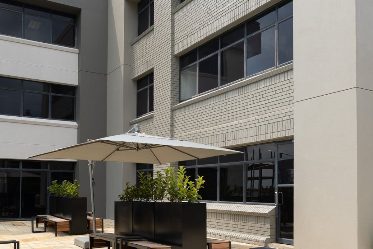 A well-maintained commercial courtyard featuring paved flooring and a multi-story building facade with modern aluminum-framed windows.