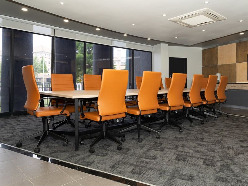 A professional commercial boardroom featuring large windows, recessed lighting, ducted air conditioning, and built-in cabinetry, providing a modern and functional workspace.