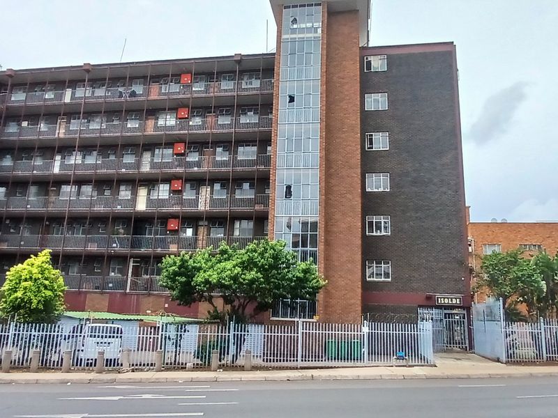 Exterior view of the Isolde apartment building featuring a brick facade, multiple balconies, and secure perimeter fencing.