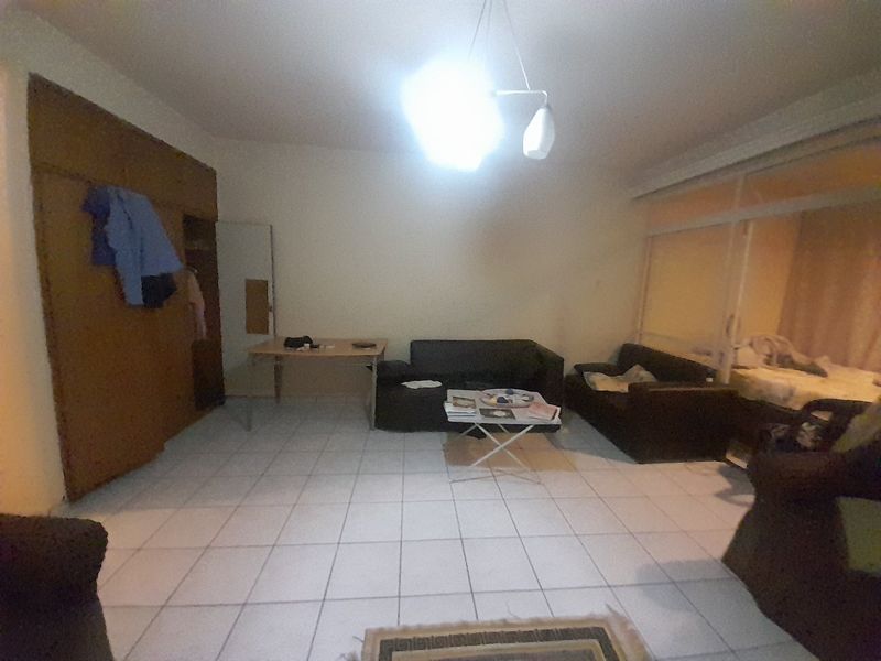 A living room area featuring tiled flooring, a built-in cupboard, and a sliding glass door leading to an adjacent space.