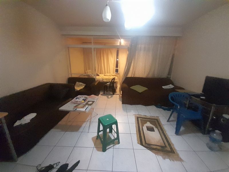 A living room area featuring tiled flooring and a sliding glass partition, providing a functional space with potential for modernization.