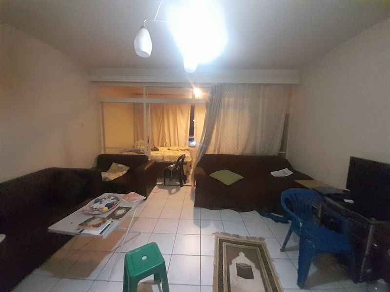 A living room area featuring tiled flooring and a sliding glass door leading to an adjacent space, requiring cosmetic updates to improve appeal.