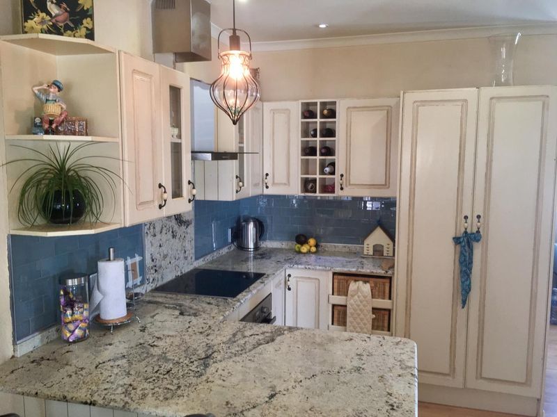 A well-appointed kitchen featuring granite countertops, subway tile backsplash, built-in oven, cooktop, and custom cabinetry with integrated wine storage.