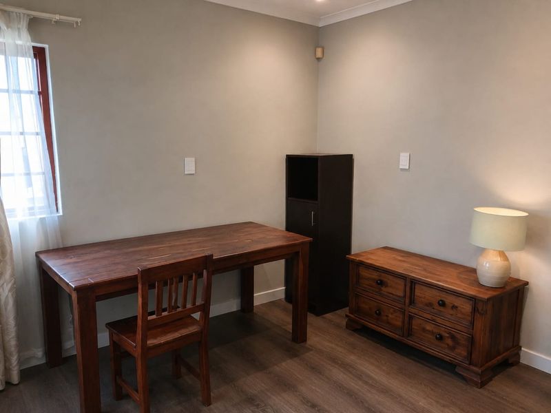 A well-maintained bedroom featuring laminate flooring, neutral wall tones, and coving, providing a clean and functional living space.