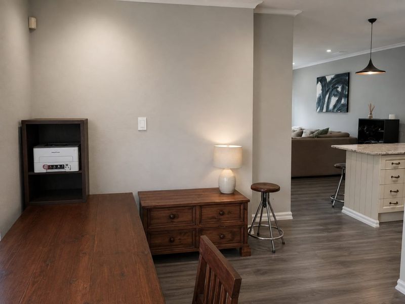 Open plan living area featuring durable laminate flooring, a central kitchen island with pendant lighting, and neutral wall finishes.