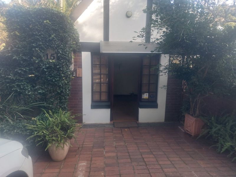 Front entrance of a commercial property featuring a brick facade, paved driveway, and timber-framed windows.