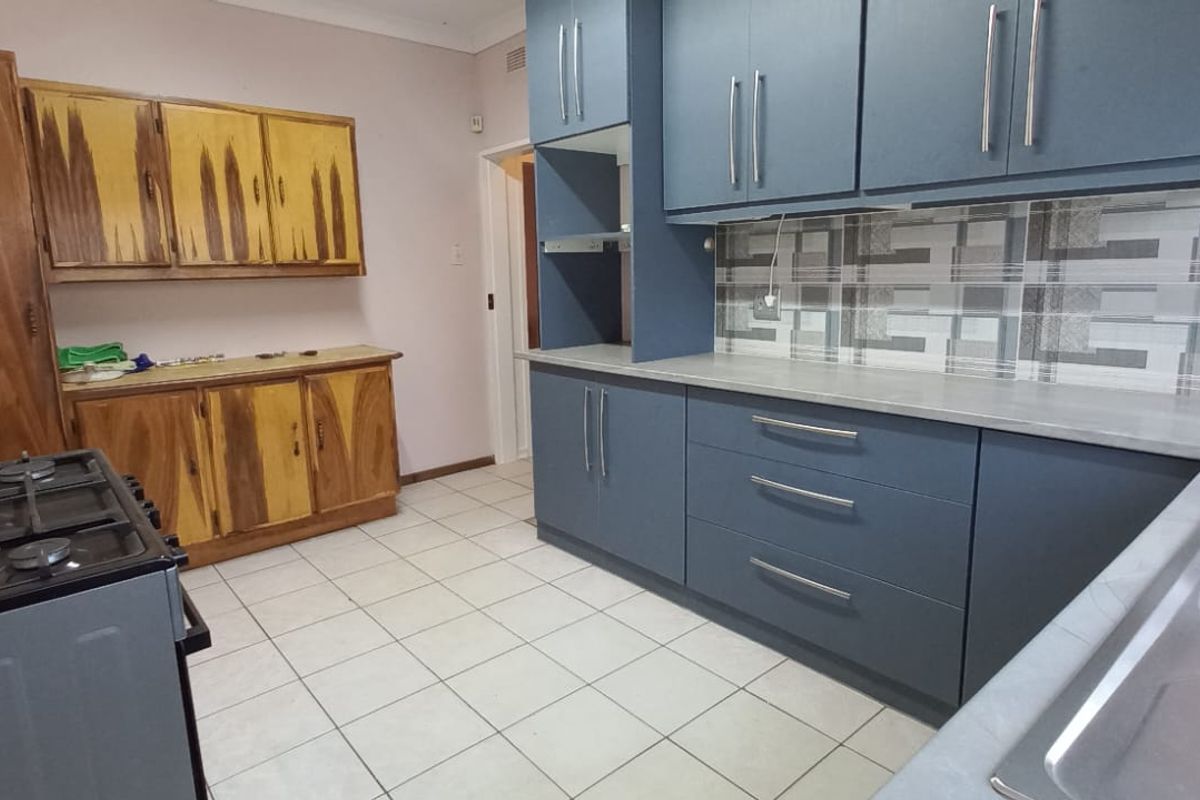 Kitchen featuring a mix of modern blue cabinetry and traditional wooden cupboards, tiled flooring, and a double bowl sink.