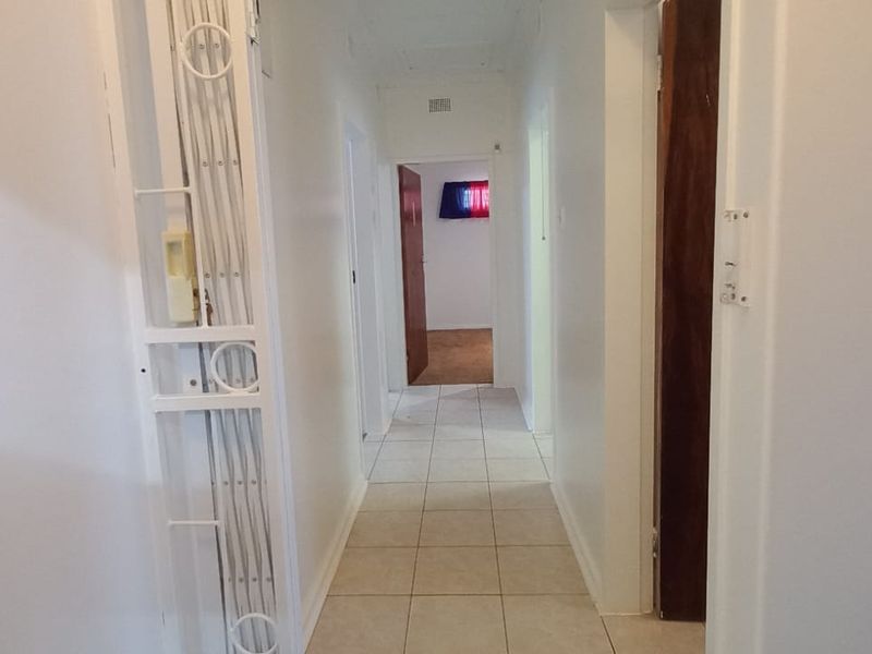 A functional hallway featuring tiled flooring and access to multiple rooms, providing a clean and neutral transition space within the home.
