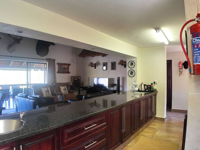 Open plan kitchen and living area featuring dark timber cabinetry, granite countertops, and direct access to an outdoor patio through sliding glass doors.