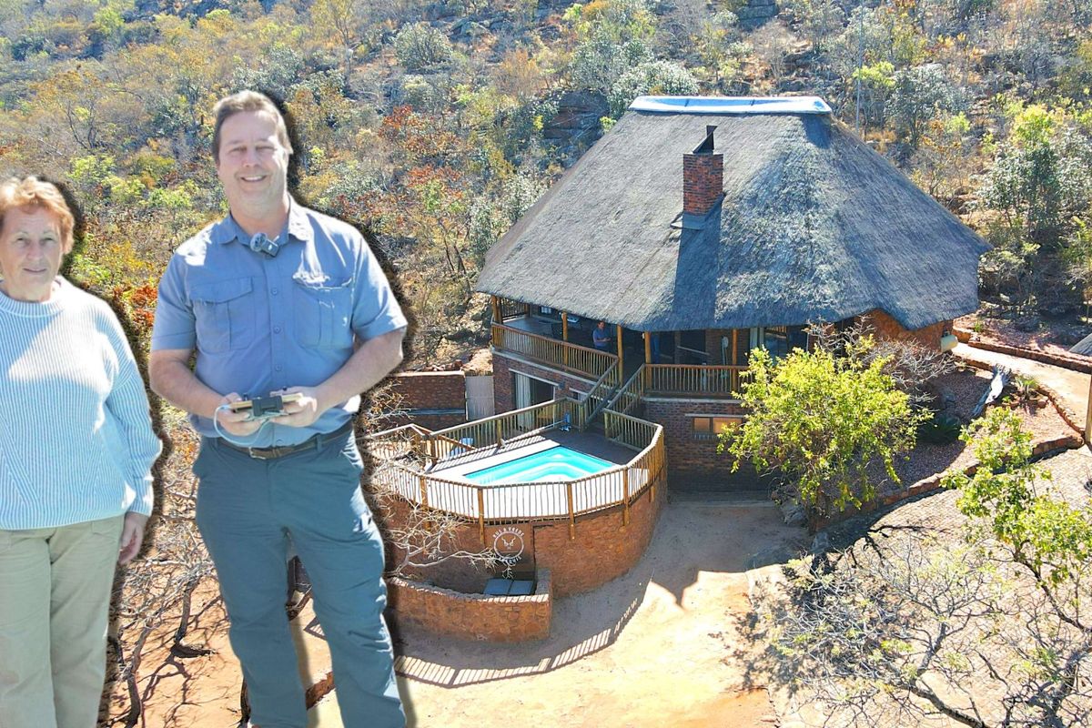 Aerial view of a thatched-roof property featuring a raised wooden deck and swimming pool, set within a natural bushveld landscape.
