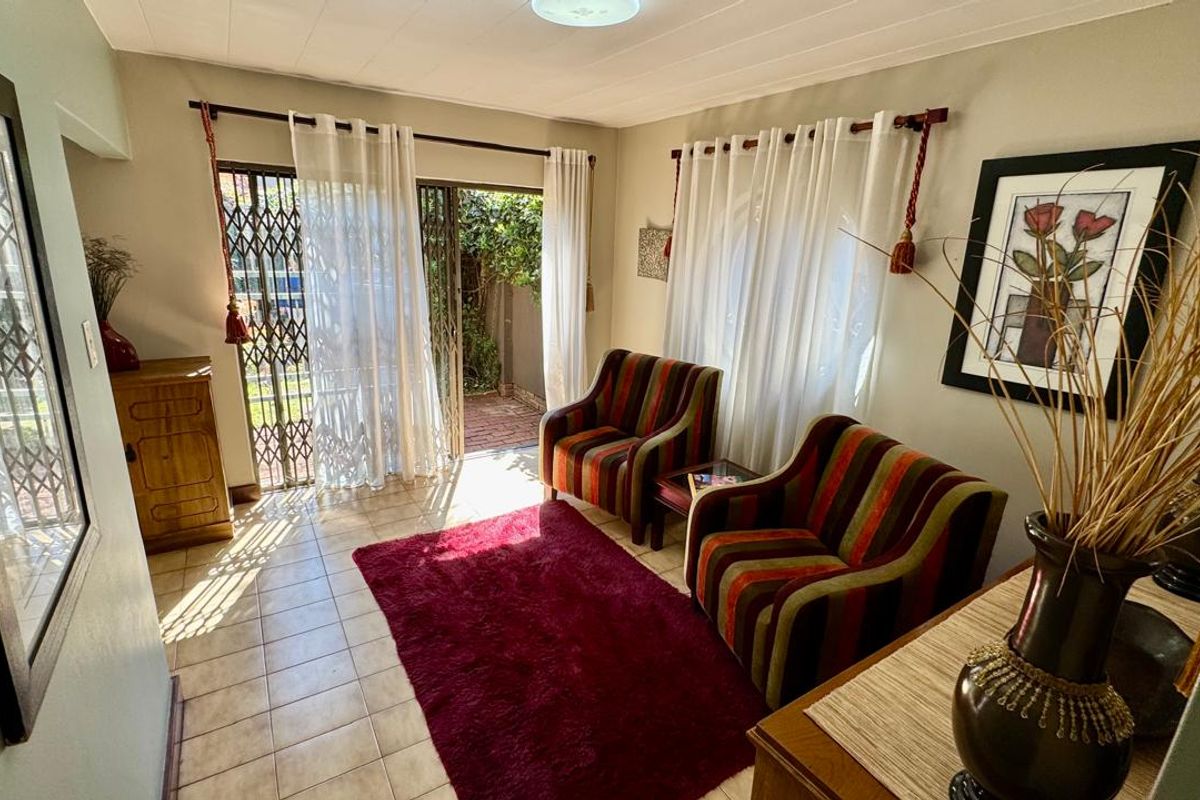 A bright living room featuring tiled flooring and a sliding glass door with a security gate, providing direct access to the outdoor area.