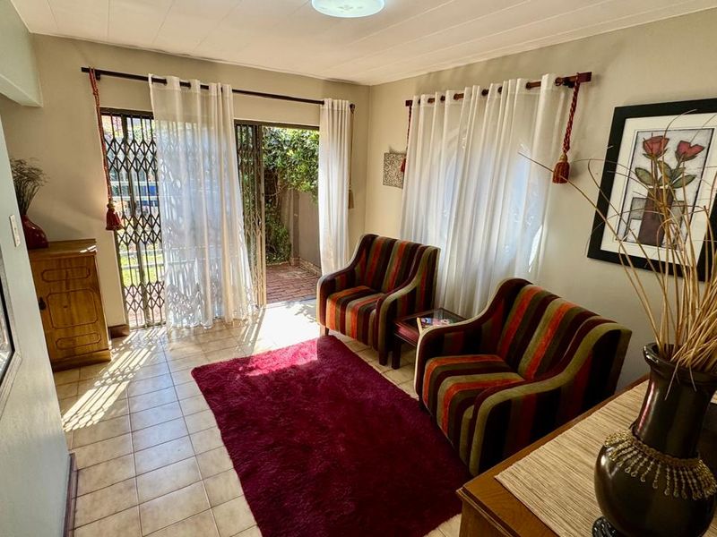 A bright living room featuring tiled flooring and a sliding glass door with a security gate, providing direct access to the outdoor area.