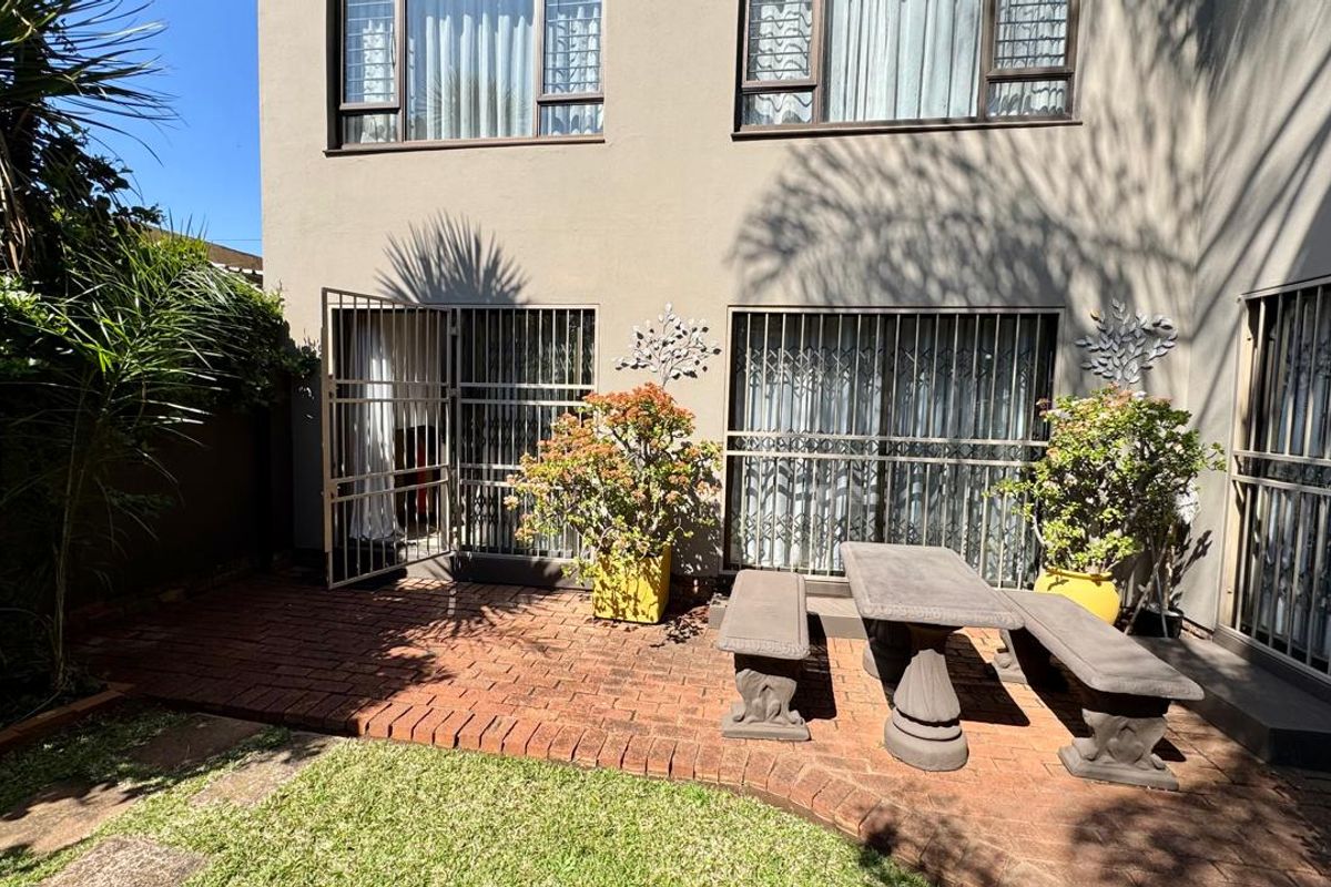 A rear townhouse patio featuring brick paving, security gates, and access to the interior living space.