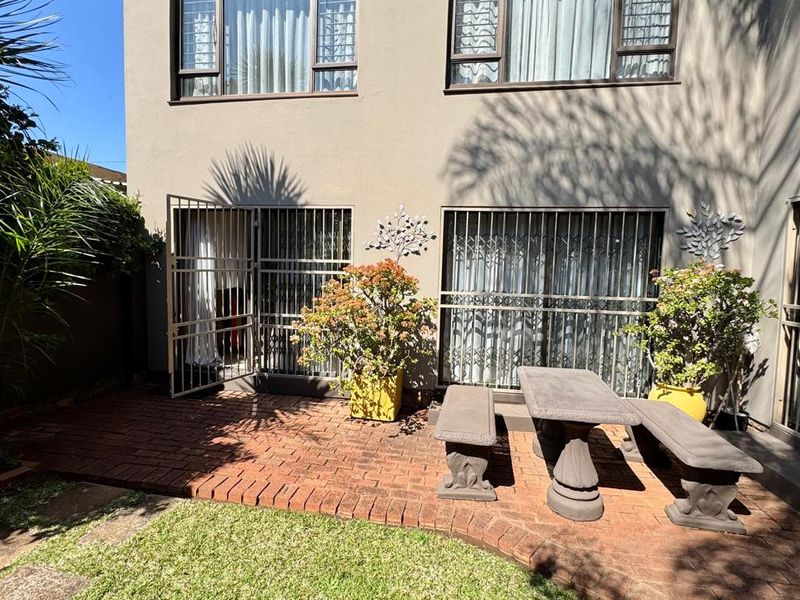 A rear townhouse patio featuring brick paving, security gates, and access to the interior living space.