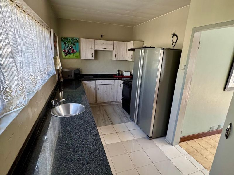 A functional kitchen featuring granite countertops, built-in cabinetry, and tiled flooring, offering a practical layout with direct access to adjacent living areas.