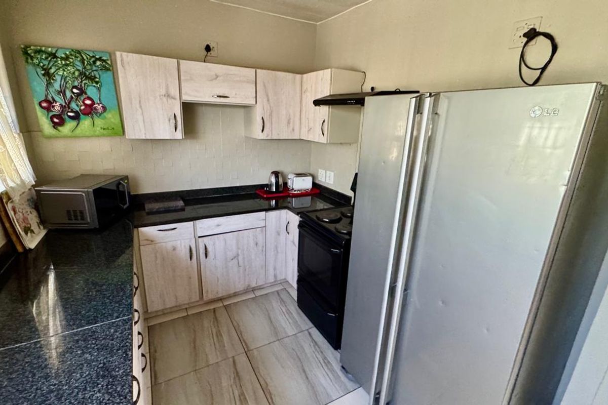 Compact kitchen featuring light wood-look cabinetry, dark granite countertops, and tiled flooring, providing a functional workspace.