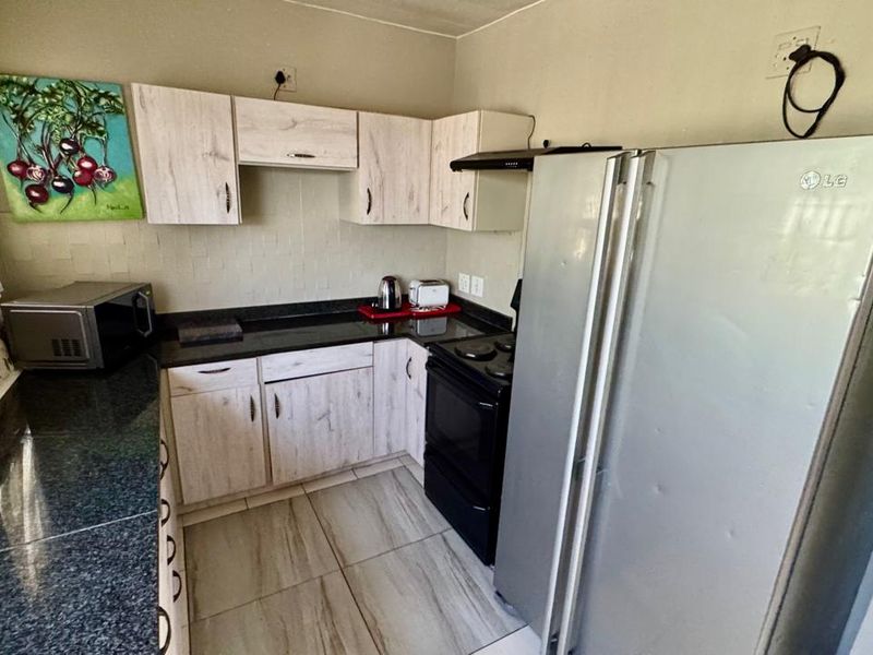 Compact kitchen featuring light wood-look cabinetry, dark granite countertops, and tiled flooring, providing a functional workspace.