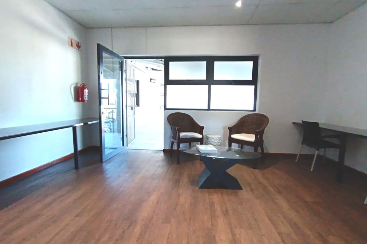 A functional office space featuring laminate flooring, built-in desk surfaces, and direct access to an outdoor area through a glass door.