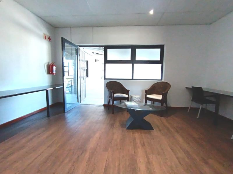 A functional office space featuring laminate flooring, built-in desk surfaces, and direct access to an outdoor area through a glass door.