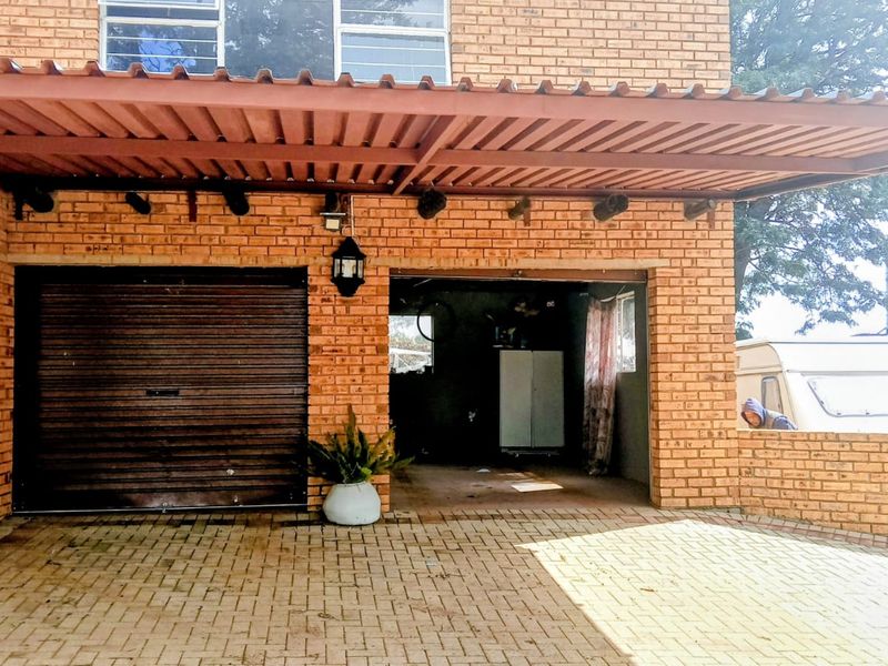 Exterior view of a brick garage featuring a covered carport area and a paved driveway entrance.