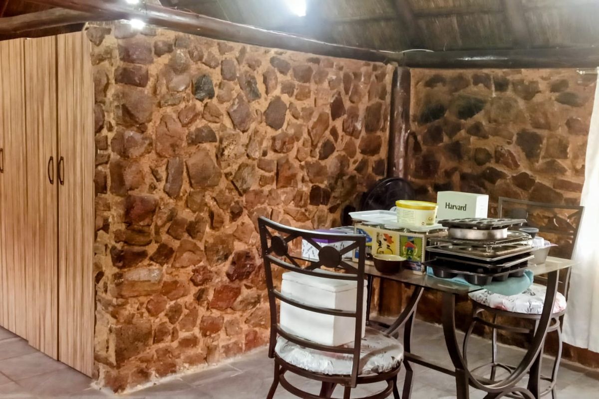 A rustic living area featuring a distinctive exposed stone wall, traditional thatched ceiling, and built-in wooden cabinetry, offering a unique farm-style aesthetic.
