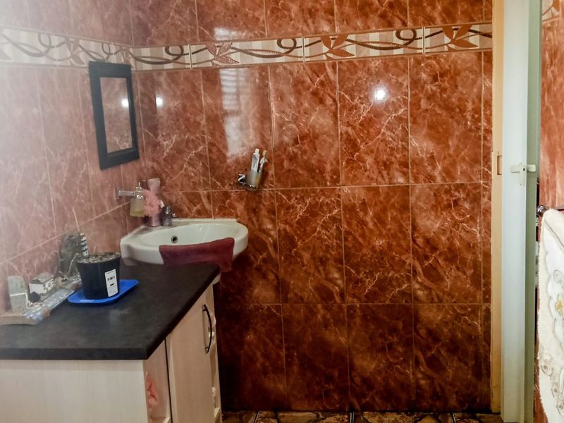 A bathroom featuring full-height brown marble-effect wall tiles, a vanity cabinet with a basin, and a wall-mounted towel rail.