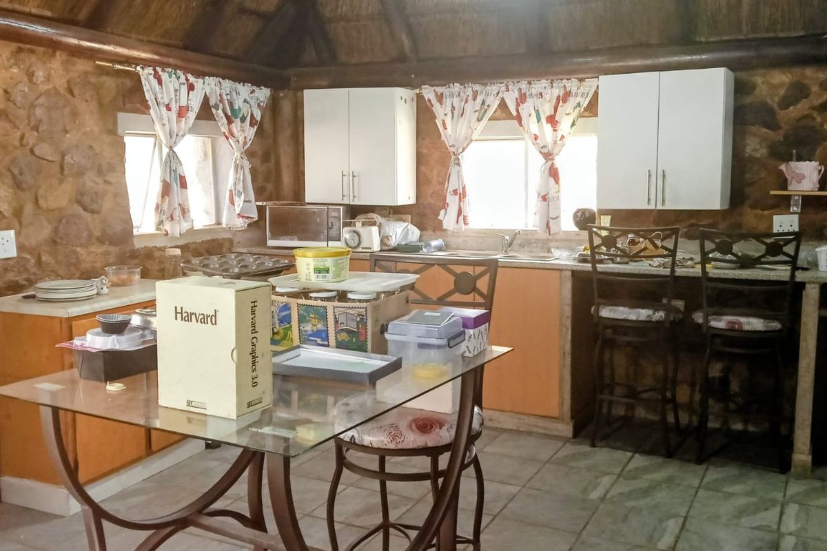 Rustic kitchen featuring stone walls, a traditional thatch ceiling, and built-in cabinetry with a functional sink area.