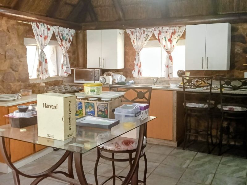 Rustic kitchen featuring stone walls, a traditional thatch ceiling, and built-in cabinetry with a functional sink area.