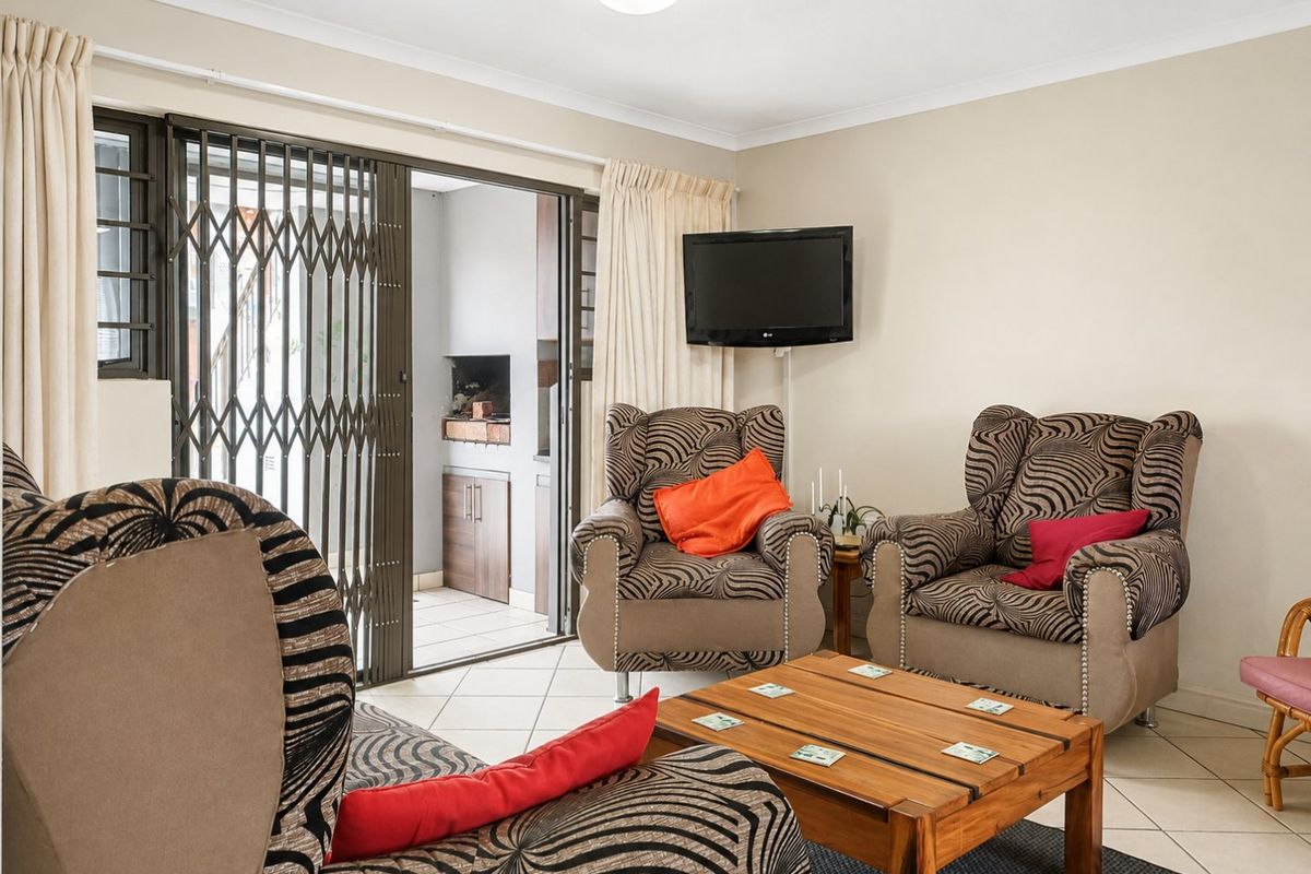 A living room featuring tiled flooring and a sliding glass door with a security gate leading to an outdoor area.