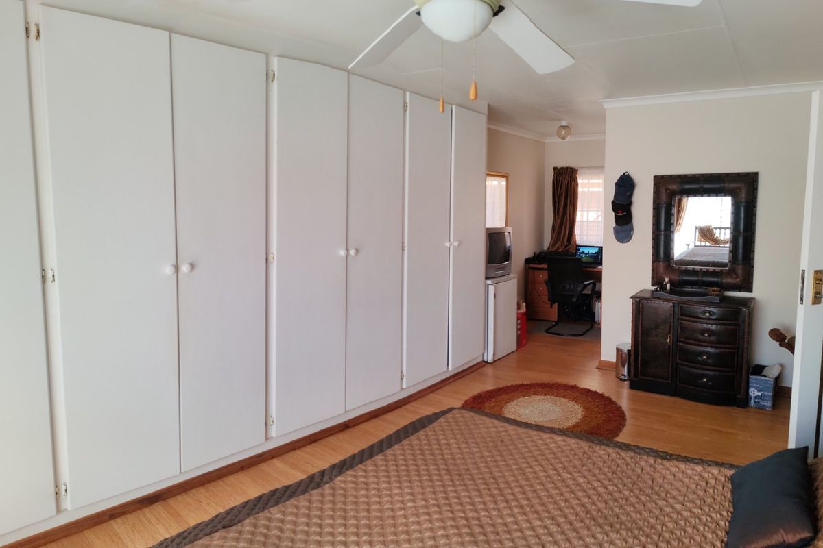 A bedroom featuring extensive built-in cupboards, laminate flooring, and a ceiling fan, offering ample storage space.