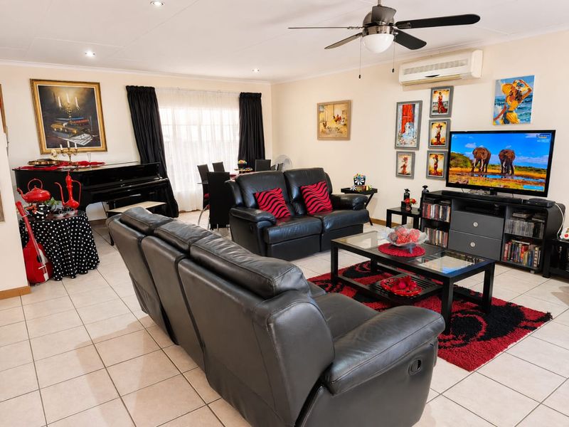 Spacious living room featuring tiled flooring, a ceiling fan, and a wall-mounted split-system air conditioner.