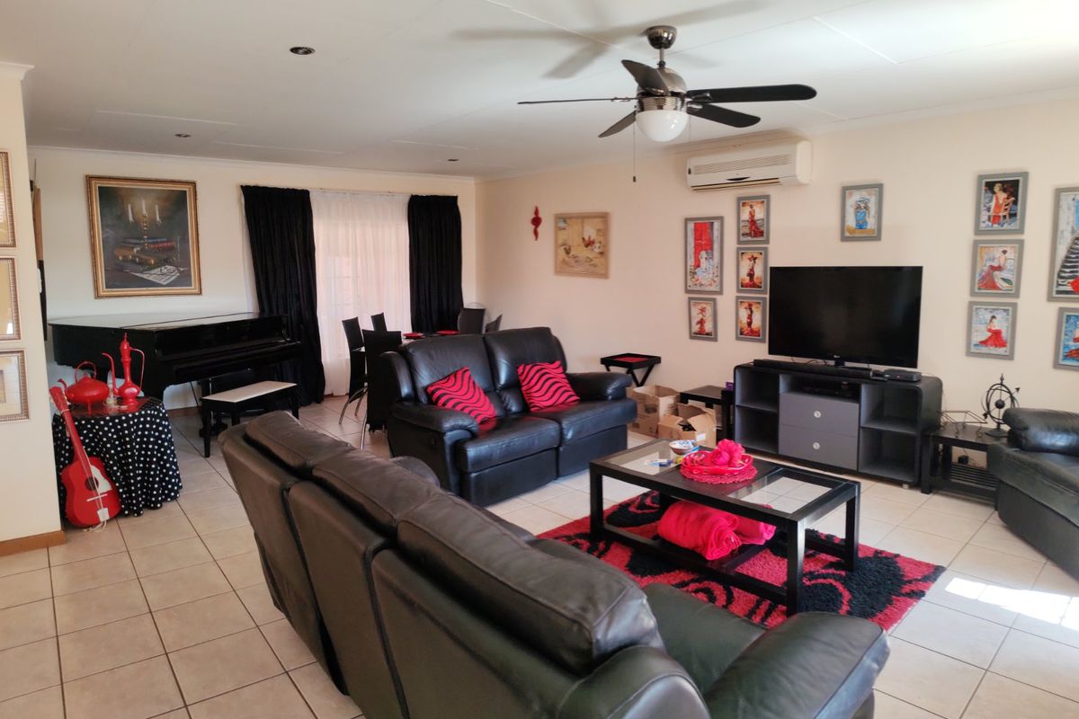 Spacious living room featuring tiled flooring, a ceiling fan, and a wall-mounted air conditioning unit, providing a comfortable and functional living space.
