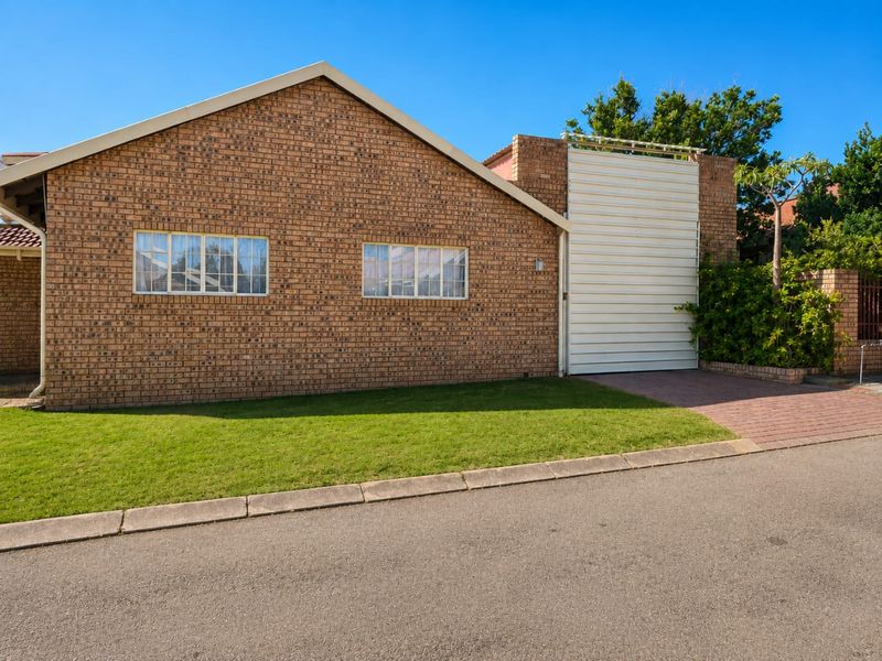 Front view of a face brick house featuring a garage, paved driveway, and a well-maintained lawn.