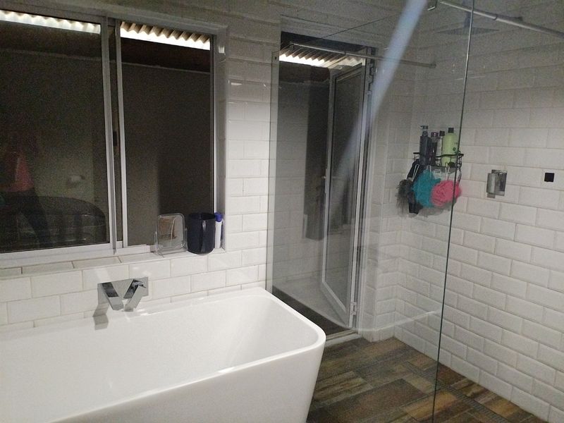 Modern bathroom featuring a freestanding bathtub, a spacious walk-in shower with glass screen, and contemporary subway tile finishes.