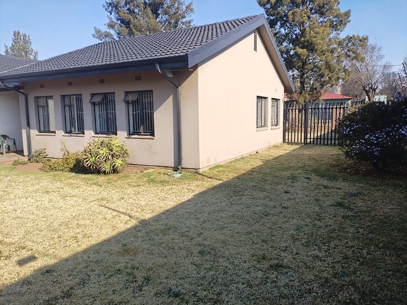 A view of the rear exterior of the house featuring a tiled roof, security bars on windows, and a private garden area.