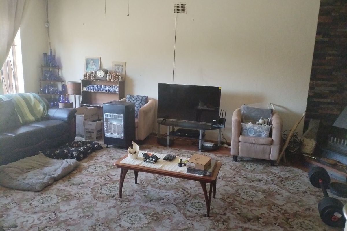 A living room featuring a stone fireplace and carpet flooring, offering a spacious layout ready for modernization and updated finishes.