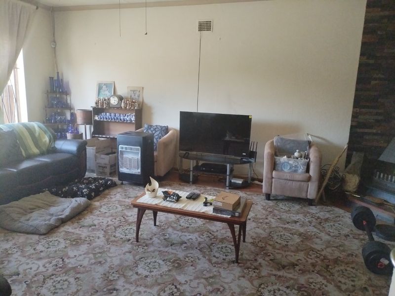 A living room featuring a stone fireplace and carpet flooring, offering a spacious layout ready for modernization and updated finishes.