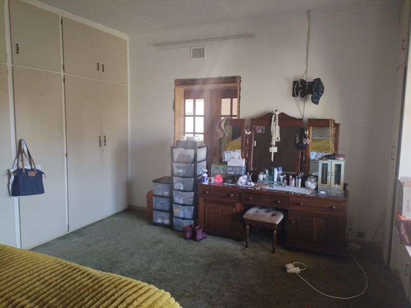 Bedroom featuring built-in cupboards and carpet flooring, requiring attention to the unfinished door frame and exposed electrical wiring.