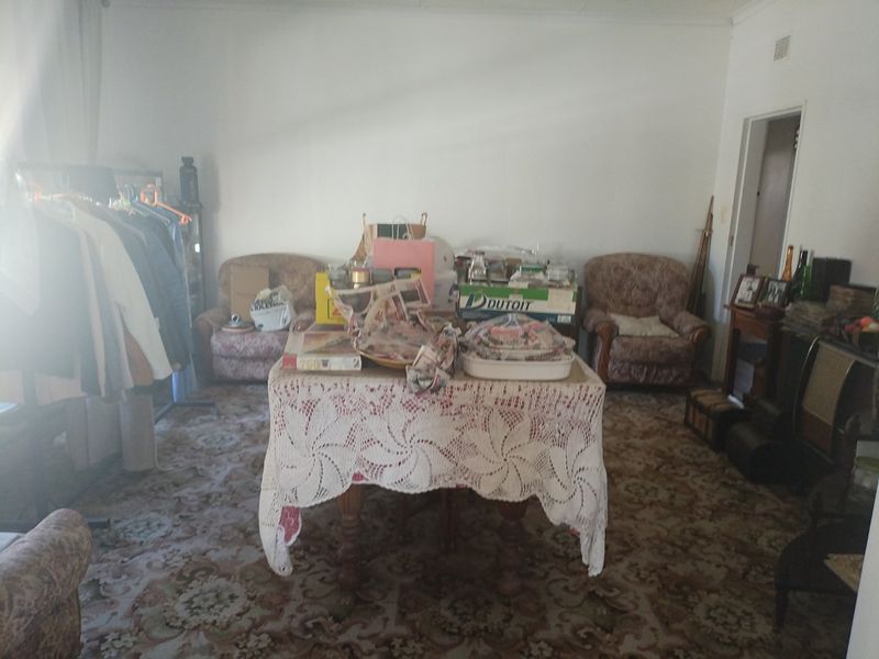A living room space featuring carpet flooring, currently used for storage and general living purposes.