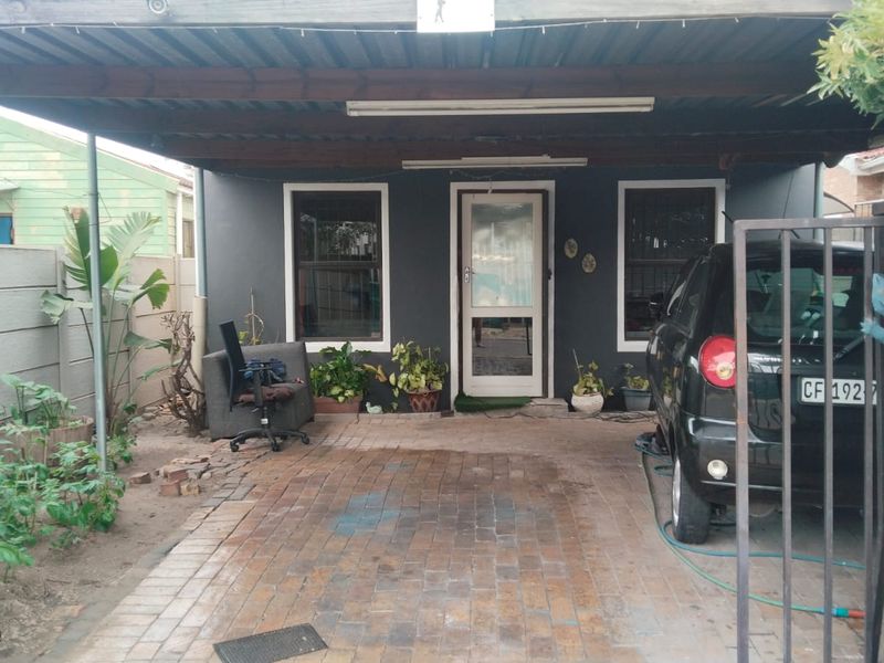 Front exterior view featuring a covered carport, paved driveway, and secure entrance with security bars.