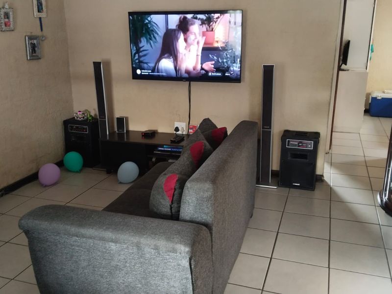 A living room area featuring ceramic floor tiles and a wall-mounted television setup.