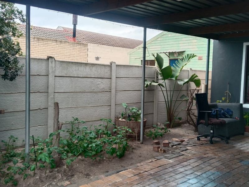 A covered outdoor patio area featuring paved flooring and a precast concrete boundary wall, offering a functional space for outdoor living.