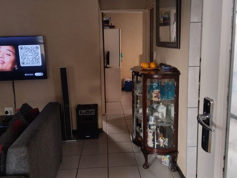 A view of a living room area with tiled flooring, leading into a hallway and adjacent room.