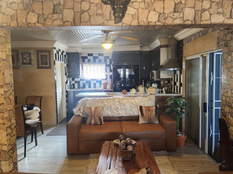 Open-plan living and kitchen area featuring stone-clad architectural details, tiled backsplash, and direct access to an outdoor space via sliding glass doors.