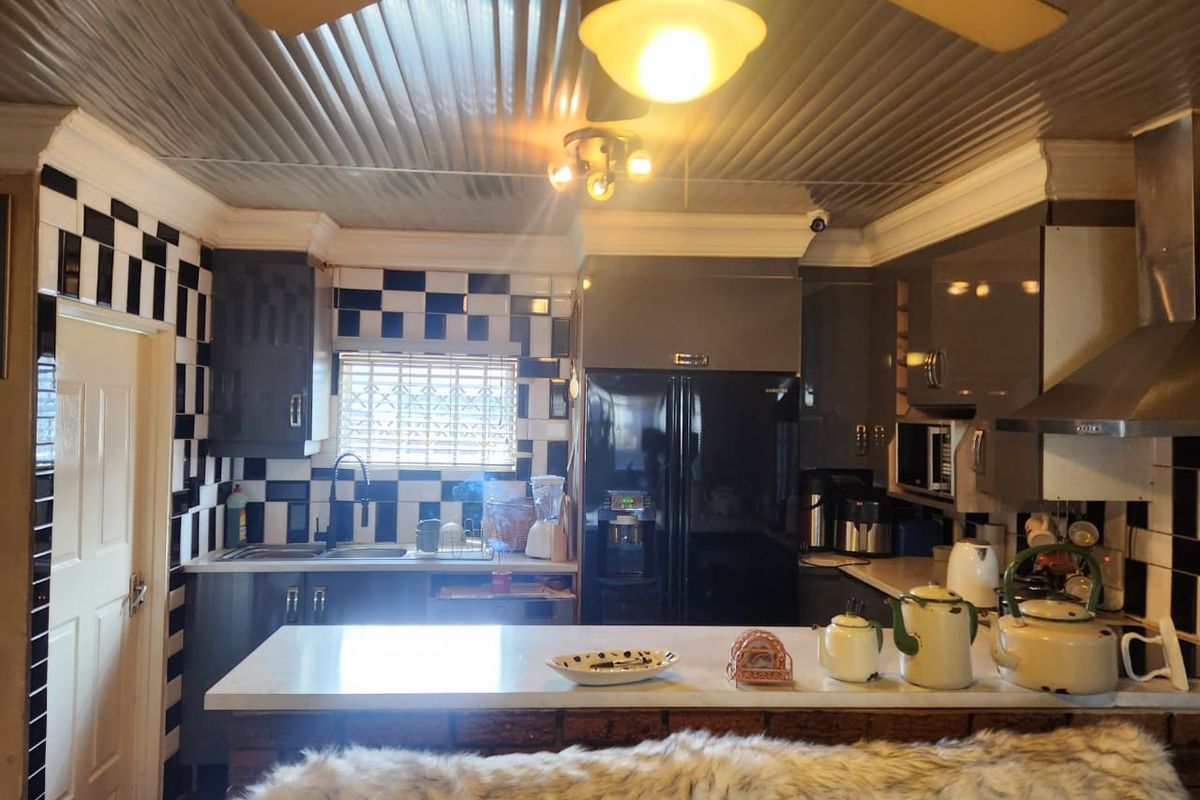 A functional kitchen featuring built-in cabinetry, stone countertops, a stainless steel extractor fan, and a distinctive checkerboard tiled backsplash.