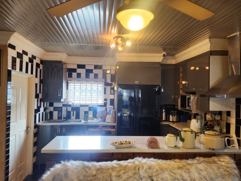 A functional kitchen featuring built-in cabinetry, stone countertops, a stainless steel extractor fan, and a distinctive checkerboard tiled backsplash.