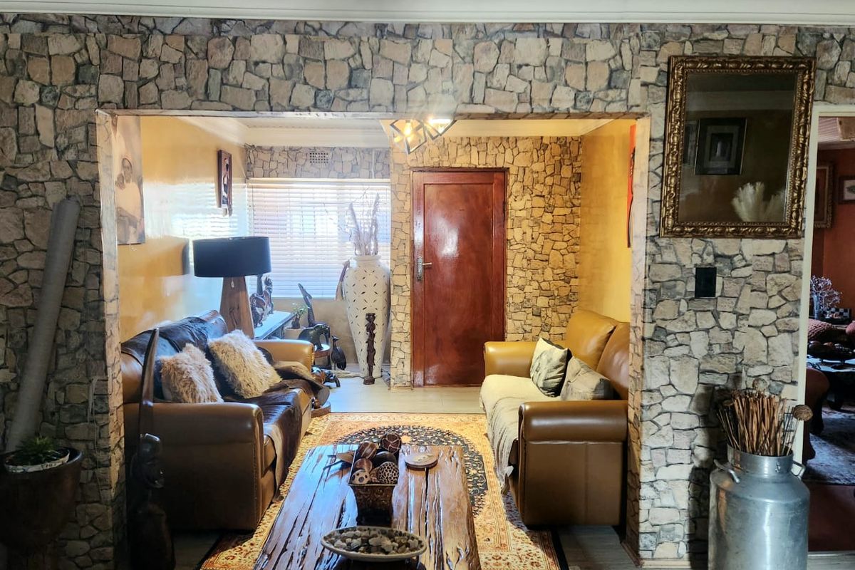 A living room featuring stone-clad feature walls, laminate flooring, and a timber door, offering a rustic aesthetic with potential for modern updates.