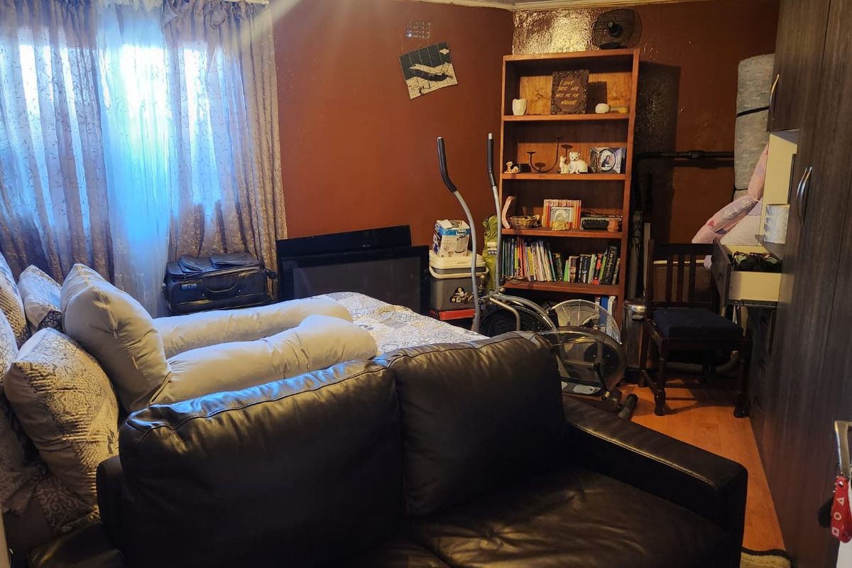 A bedroom featuring laminate flooring, a built-in wardrobe, and a tongue and groove ceiling, currently requiring cosmetic updates to the wall finishes.