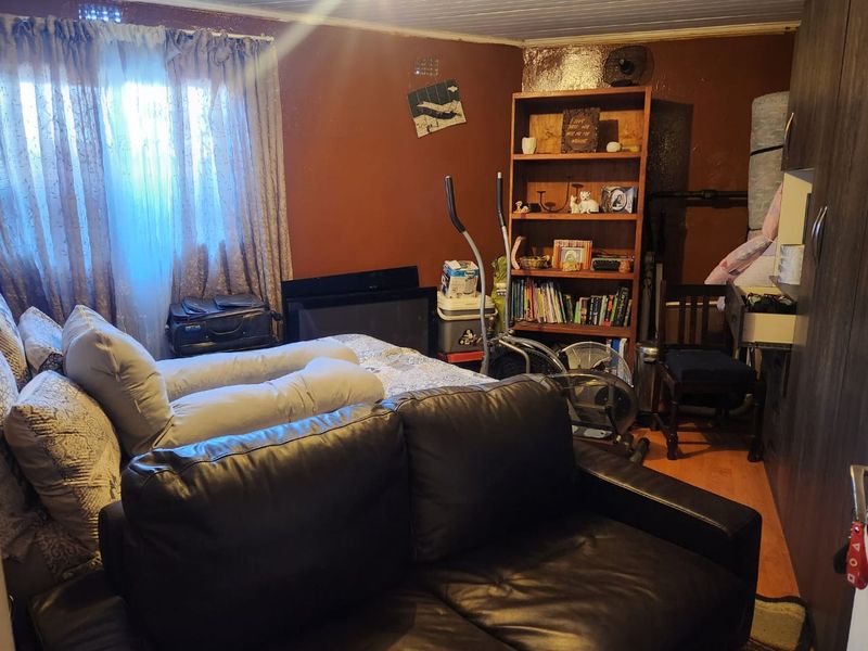 A bedroom featuring laminate flooring, a built-in wardrobe, and a tongue and groove ceiling, currently requiring cosmetic updates to the wall finishes.